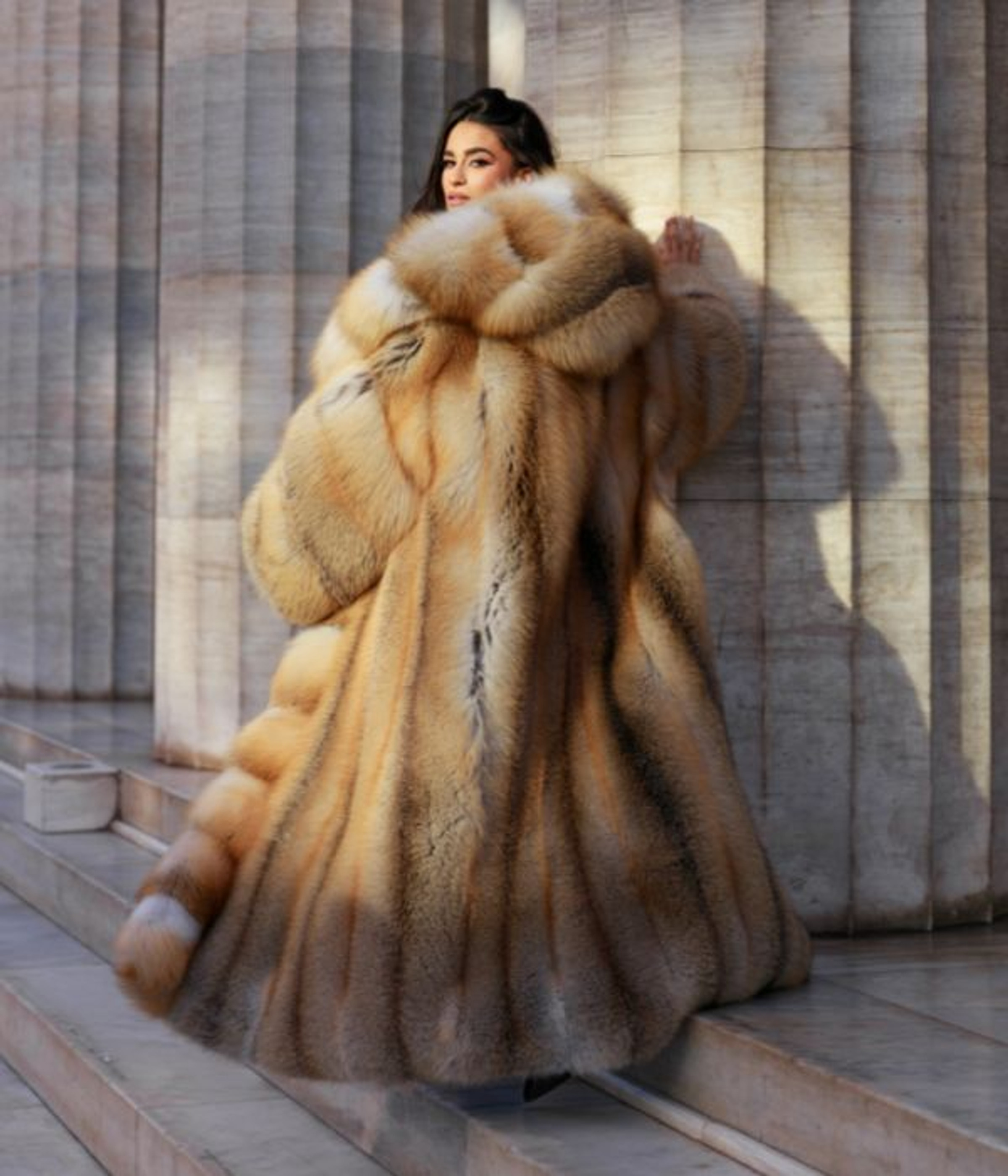 A dramatic golden fox coat by Velur Boutique, against marble columns
